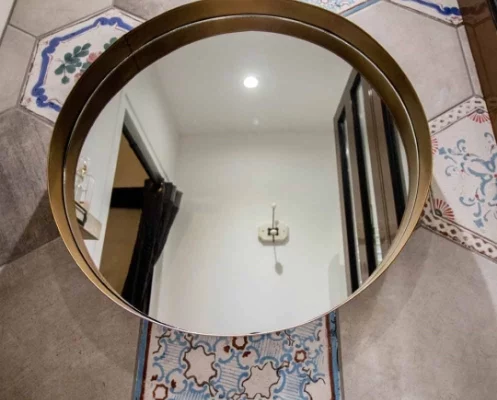 Miroir rond sur carrelage hexagonal.